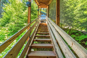 A wooden staircase leading to a covered area surrounded by lush greenery. - Cedar Dream | Spacious Family Retreat Near Lake Wenatchee | Sleeps 10 (Leavenworth)