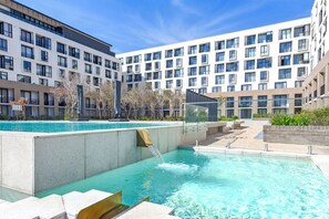 Un hôtel moderne doté d’une piscine, de nombreux balcons et offrant une vue sur un ciel dégagé.