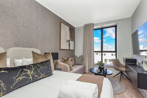 Ein modernes Hotelzimmer mit einem großen Bett, einer Sitzecke, einem Schreibtisch und Blick auf die Stadt.