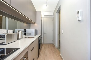 Eine moderne Küche mit Mikrowelle, Toaster und Wasserkocher, Holzboden und weißer Tür.