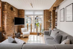 Ein Wohnzimmer mit einer Couch, einem Couchtisch, einem Fernseher und einer Ziegelwand.