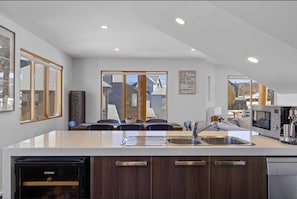 A modern kitchen with a built-in dishwasher, a large island with a sink, and a view of the outside.