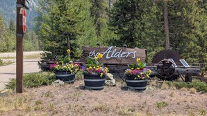Un cartello di legno con scritto 'the Alders', circondato da vasi di fiori e un trattore d'epoca.