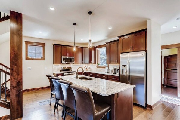 A modern kitchen with a central island, stainless steel appliances, and dark wood cabinets. - Alders Haven w/Priv Hot Tub, Access to Slopes (Keystone)