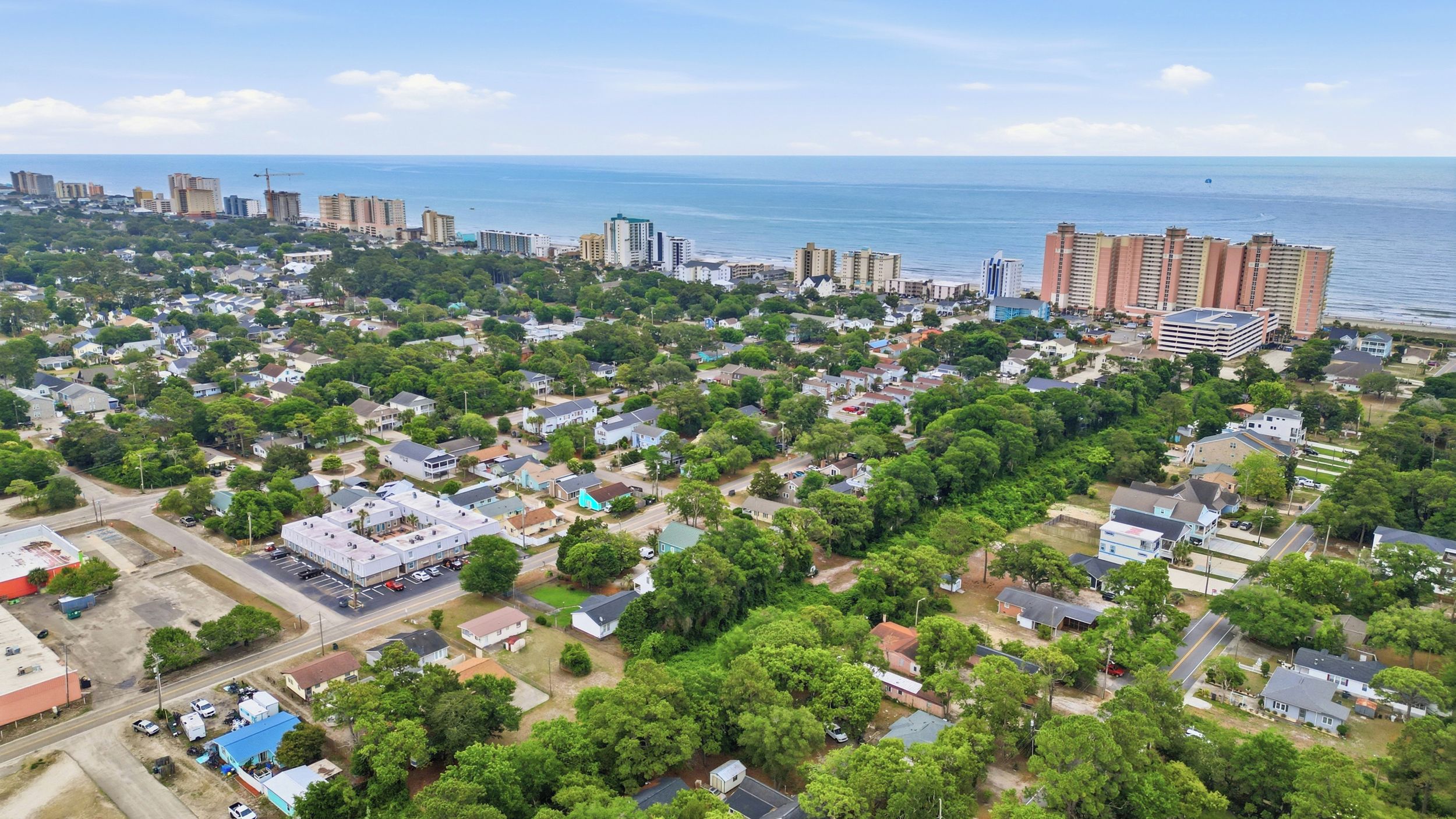 Vue aérienne d’une ville côtière avec des quartiers résidentiels densément peuplés, une marina et des immeubles de grande hauteur.