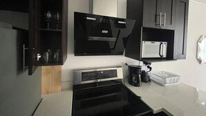 Une cuisine moderne équipée d’un four encastré, d’un four à micro-ondes et d’une machine à café.