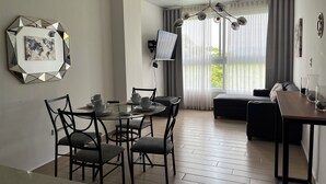 Un espace de vie moderne comprenant un coin repas, un canapé et un téléviseur fixé au mur.