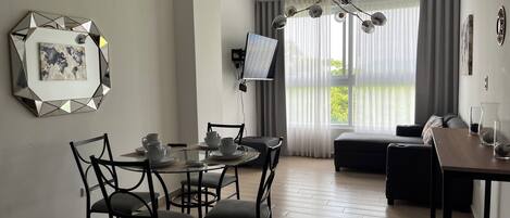 A modern living space with a dining area, a sofa, and a TV mounted on the wall.