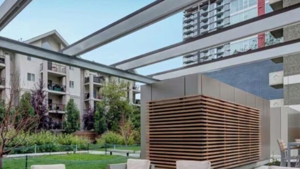 Uma área de estar moderna ao ar livre, com sofás, uma mesa de centro e um painel de ripas de madeira.