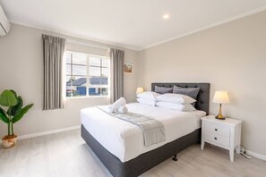A bedroom with a bed, bedside tables, a window, and a plant. - Comfortable 3-Bedroom Home in East Tamaki Heights (East Tamaki Heights)