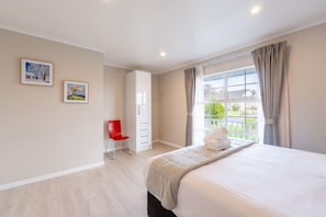 A bedroom with a bed, a red chair, a wardrobe, and a window with curtains.