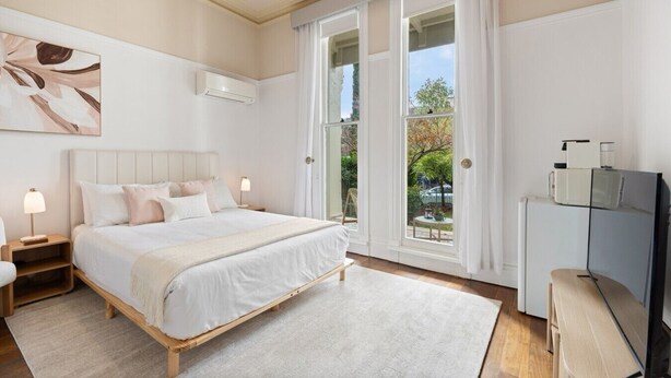 Una camera da letto con un letto, comodini, una TV e un'ampia finestra.