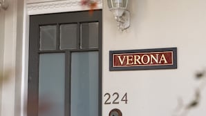 Une maison portant le numéro 224, avec une porte sombre et une enseigne sur le mur indiquant « VERONE ».