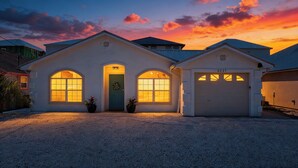 Uma casa de dois andares com garagem, janelas em arco e porta decorada com uma guirlanda.