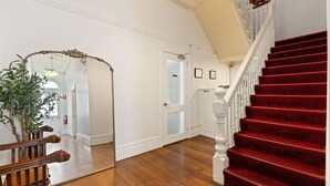 A staircase with red carpet, a wooden handrail, and a white door with frosted glass panels. - Grand Victorian Stay in the Heart of Glebe (Glebe)