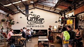 A restaurant interior with tables and chairs, a counter, and a wall with the name 'The Gruber Brewing Co.'