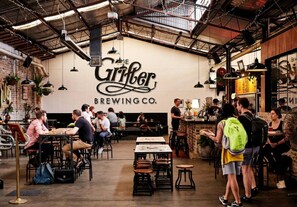 A restaurant interior with tables and chairs, a counter, and a wall with the name 'The Gruber Brewing Co.' - Charming Sunlit Terrace in Vibrant Newtown (Newtown)