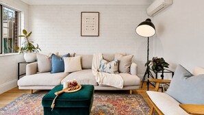A modern living room with a sofa, ottoman, and a floor lamp.