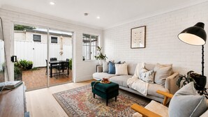 A modern living room with a sofa, coffee table, and a dining area with chairs and a table.