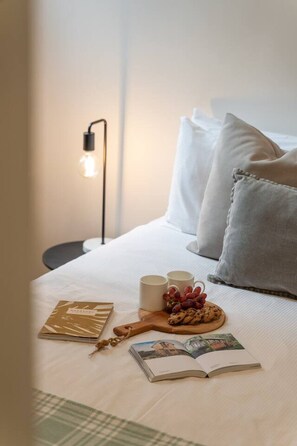 A neatly made bed with pillows, a bedside lamp, two mugs, a book, and a plate with cookies and grapes. - Charming Sunlit Terrace in Vibrant Newtown (Newtown)