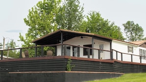 A house with a porch, a fenced deck, and a grassy yard. - Lake Seminole Retreat with Boat Slip (Sneads)