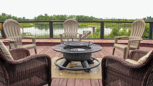 A deck with wicker chairs and a metal fire pit, overlooking a lake. - Lake Seminole Retreat with Boat Slip (Sneads)