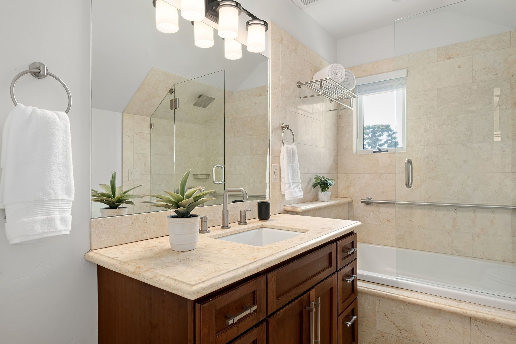 Une salle de bain moderne avec une douche à parois de verre, un lavabo doté d’un plan de travail en marbre et un grand miroir.
