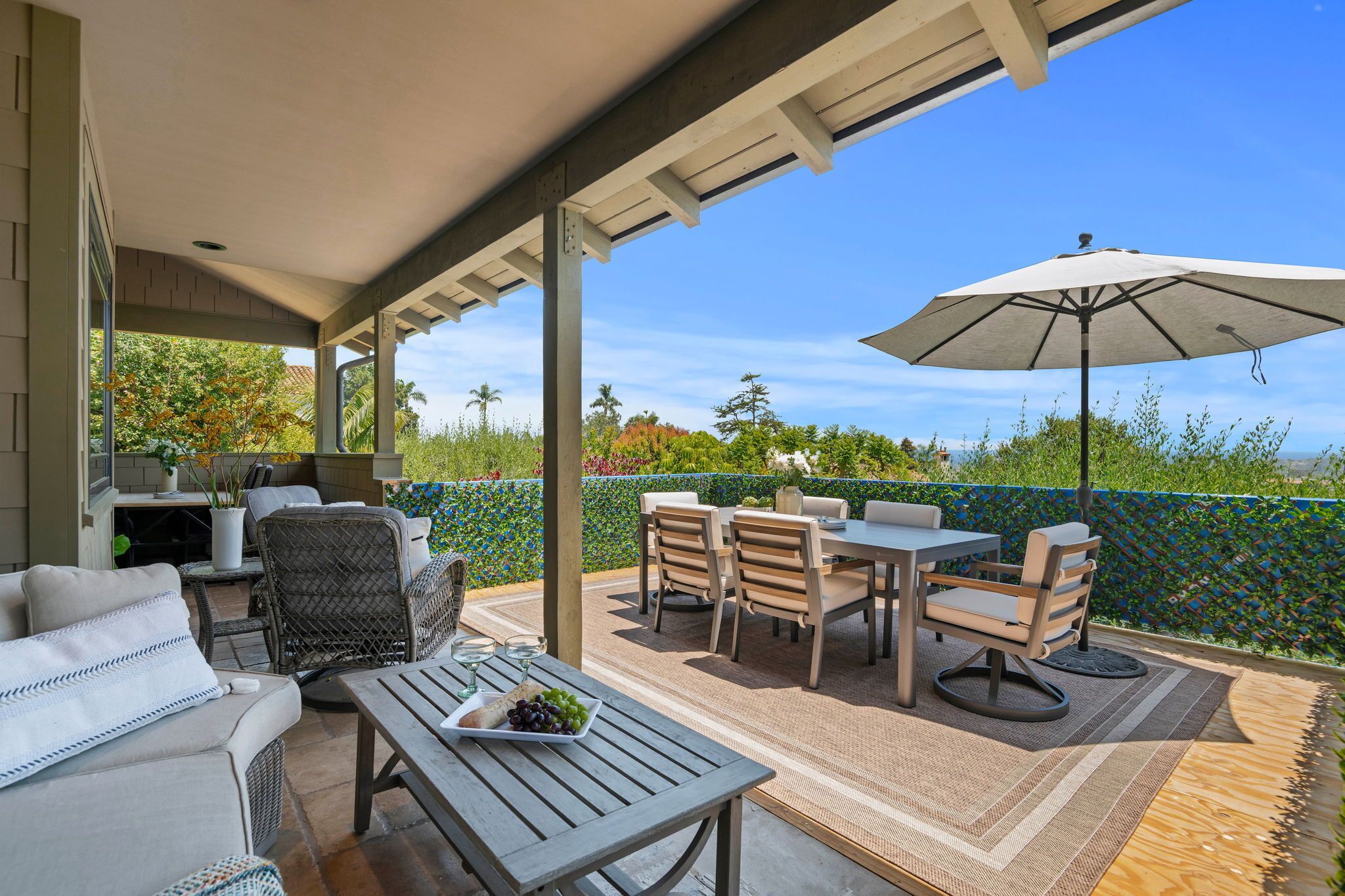 An outdoor patio with a dining set, chairs, a table, and an umbrella.