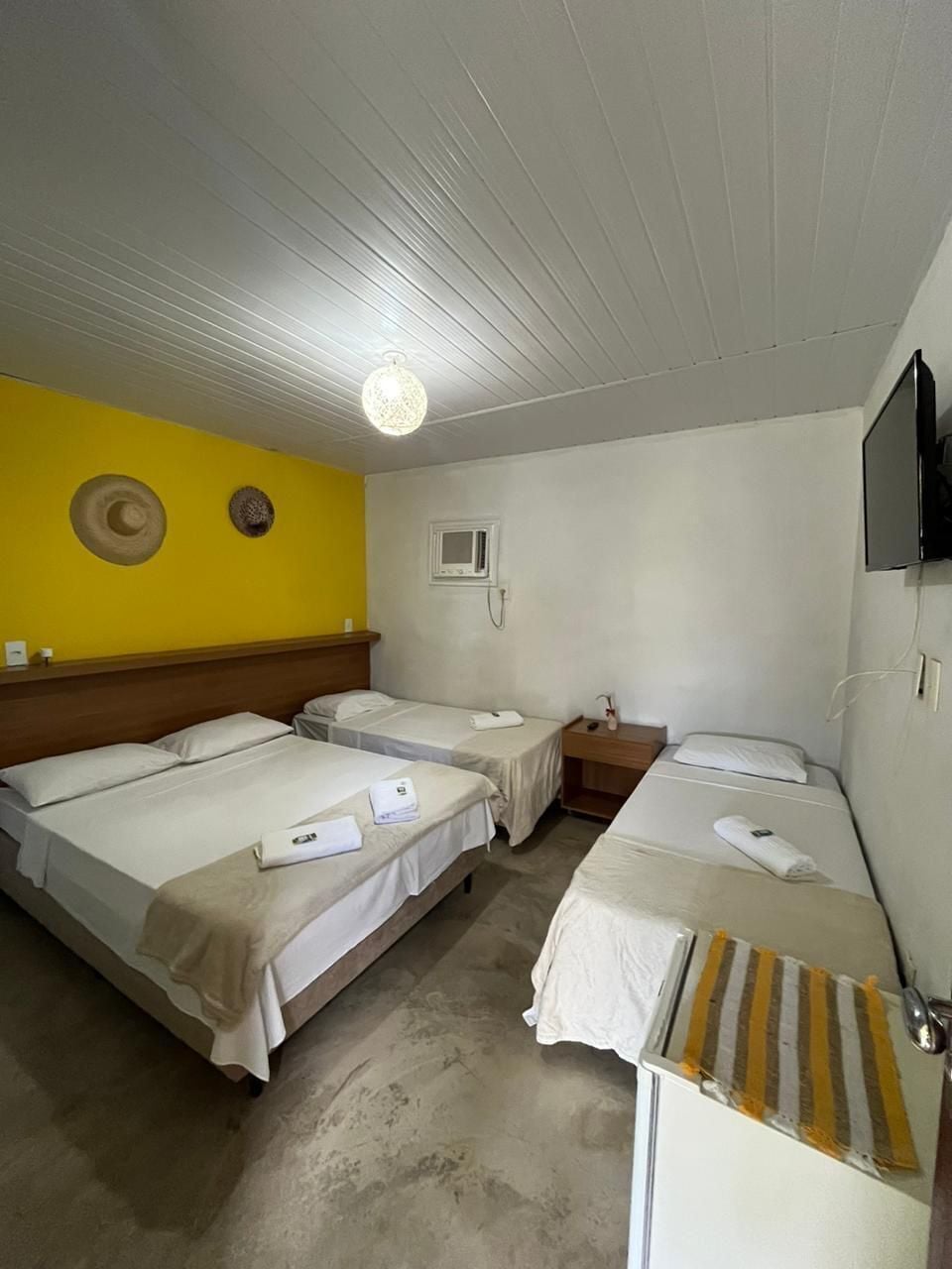 Une chambre d’hôtel avec deux lits, une petite table de chevet, un téléviseur et un radiateur fixé au mur.