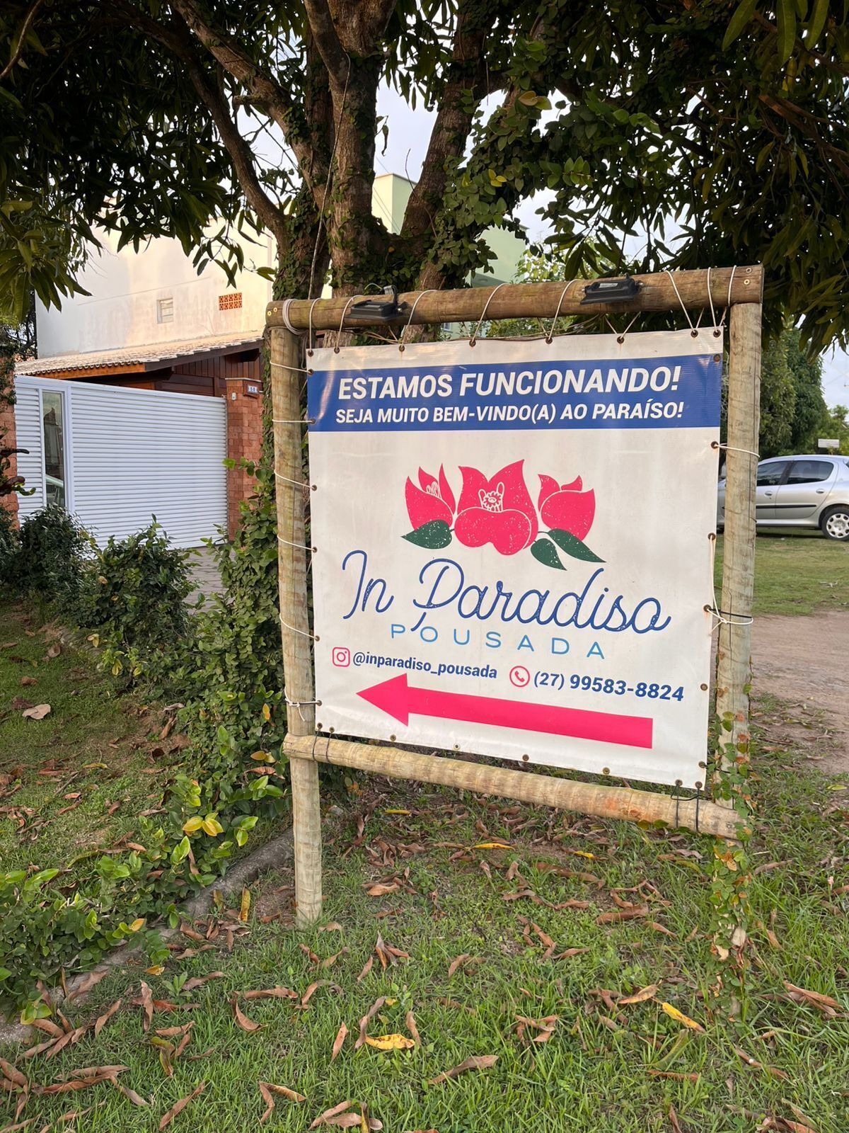 Un letrero con diseño floral, texto en portugués y un número de contacto.