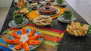 A buffet table with various dishes and drinks, a kitchen area with appliances, and a view of the outdoors. - In Paradiso  (Aracruz)