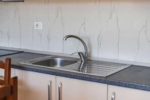 A kitchen with a stainless steel sink, a faucet, a countertop, and a wall with a marble-like pattern. - Orikum Beachside Retreat Apartment 13 by Pikhost (Orikum)