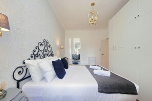 Ein ordentlich eingerichtetes Hotelzimmer mit Bett, Fernseher, Kleiderschrank und einer Kristallleuchter.