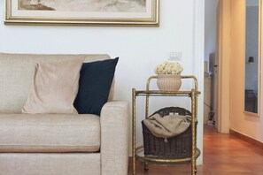 Ein Wohnzimmer mit einer Couch, einem kleinen Tisch mit einer Vase und einem Korbstuhl.