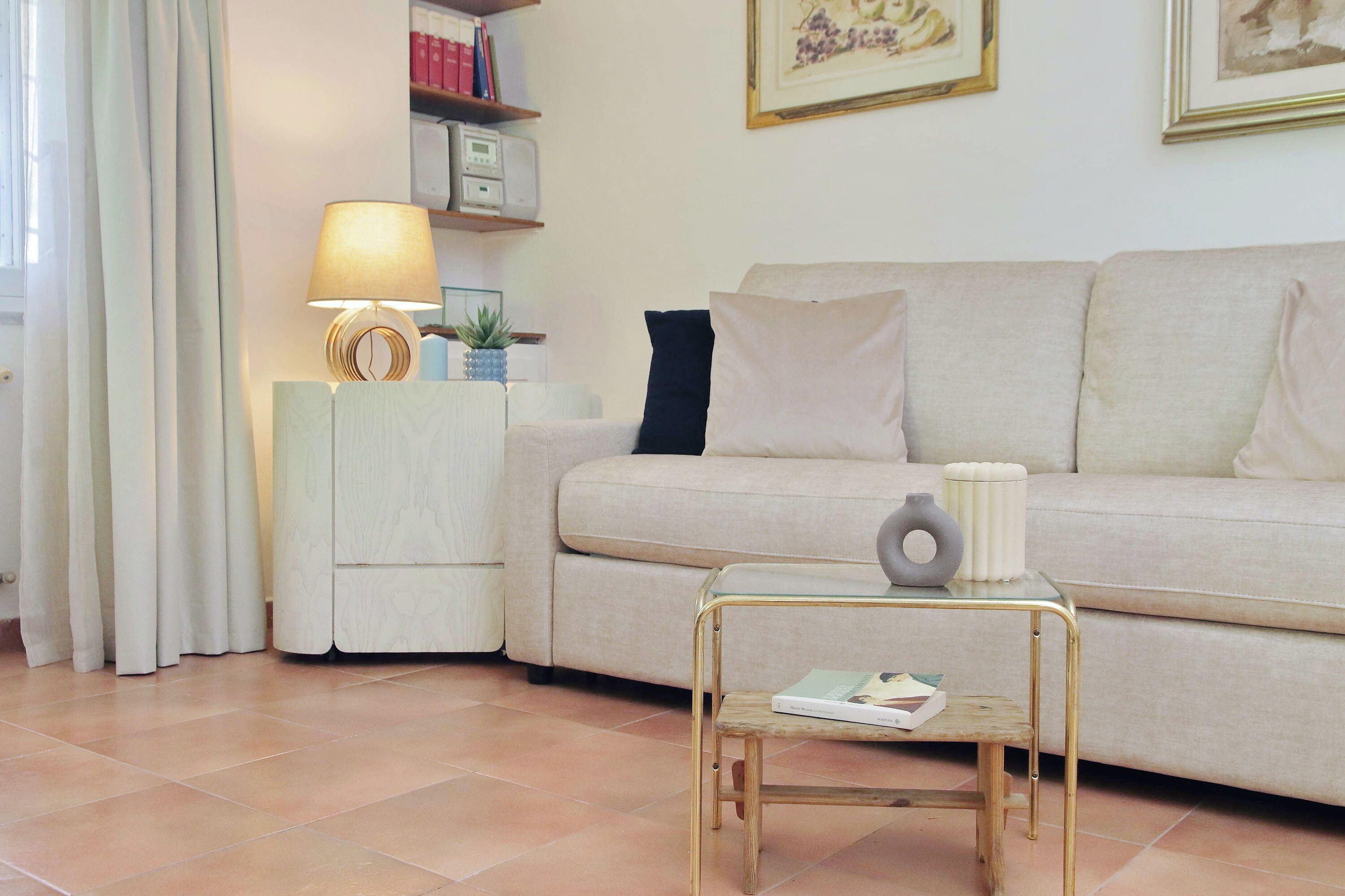 A living room with a sofa, a small table with a lamp, and a bookshelf.