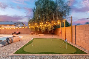 Ein Garten mit Putting-Green, Whirlpool und Lichterketten.