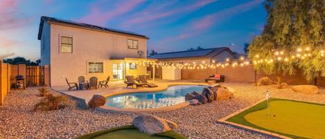 A house with a swimming pool, outdoor seating, and string lights.