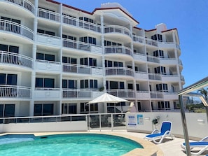 A multi-story hotel with balconies, a swimming pool, and sun loungers. - Miss A l e x l Beachfront Babe l Pool & Parking! (Alexandra Headland)