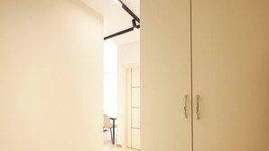 Ein Flur mit einer Tür zu einem Zimmer, einem Stuhl und einem Tisch im Hintergrund.