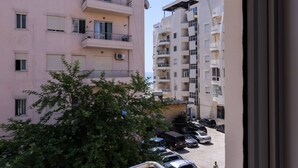 Ein mehrstöckiges Wohngebäude mit Balkonen, einem Parkplatz und einem Baum im Vordergrund.