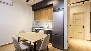 Een moderne keuken met een houten tafel en stoelen, een koelkast en een betegelde achterwand.