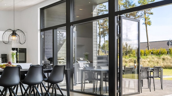 Eine moderne Küche mit Essbereich und großen Glasüren, die auf eine Terrasse im Freien führen.
