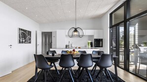Uma área de refeições moderna com uma mesa preta, cadeiras e um centro de mesa com frutas.