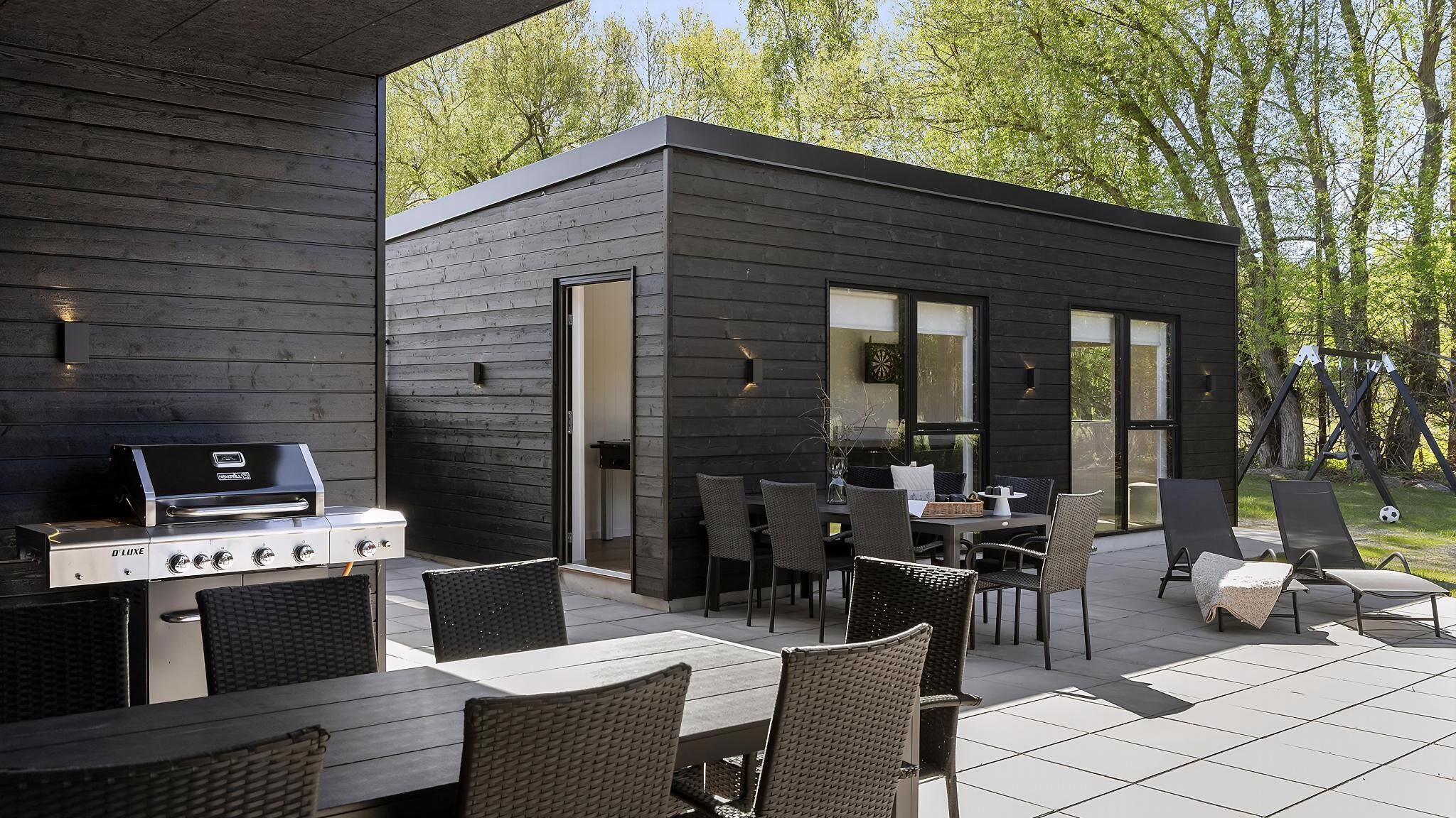 A modern outdoor patio with a grill, dining area, and lounge chairs.