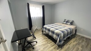 Un dormitorio con una cama, un escritorio y una silla.