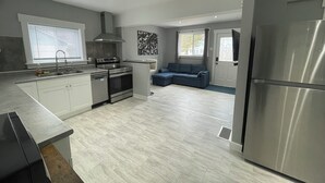 Una cocina moderna con electrodomésticos de acero inoxidable, un sofá gris y un amplio ventanal.