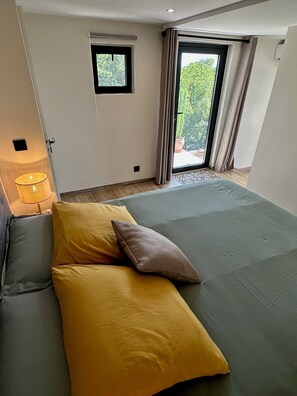 Ein Schlafzimmer mit einem Bett, einem Fenster, einer Tür und einer Lampe.