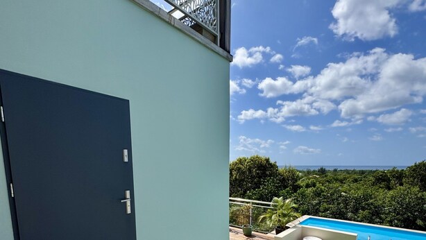 Un espacio exterior moderno con piscina, una puerta y vistas al cielo y follaje.