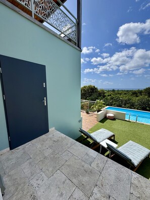 Un espace extérieur moderne doté d’une piscine, d’une porte et offrant une vue sur le ciel et la verdure.