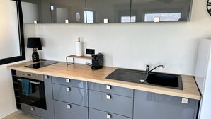 Una cocina moderna con encimera de madera, armarios integrados, un lavabo negro y una cafetera.